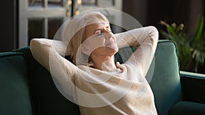 Calm happy old woman relaxing with eyes closed on couch