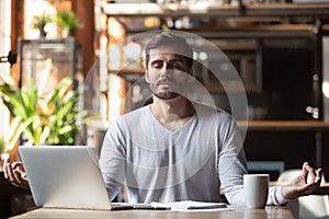 Calm healthy businessman meditate at desk feeling zen no stress