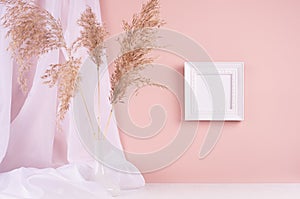 Calm home decor with square blank photo frame for text hanging on pink wall, silk curtain, fluffy reeds bouquet on white wood.