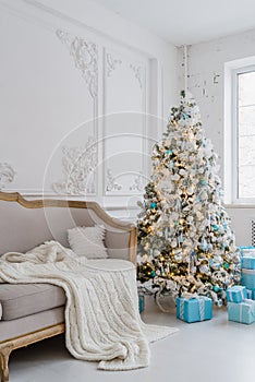 Calm image of interior luxury home living room decorated christmas tree and gifts, sofa covered with blanket.