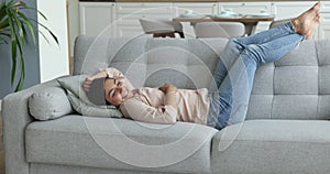 Calm Indian woman enjoy relaxation lying on sofa at home