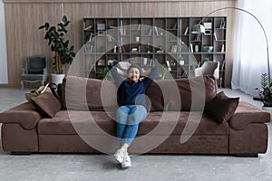 Calm Indian woman relax on sofa breathe fresh air