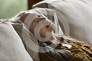 Calm lady resting with closed eyes on comfortable sofa