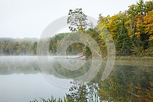 Calm lake and colorful trees in northern Minnesota on a misty autumn morning