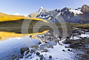 Calm lake in foot of snow-covered mountain at sunrise