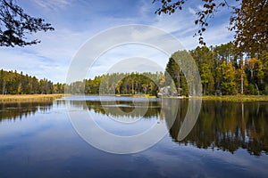 Calm lake in northern Minnesota with trees and rocks on a bright autum day