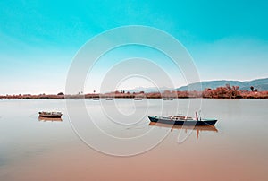 Calm lake with two fishing boats. Fresh water lagoon in Estany de cullera. Valencia, Spain