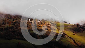 Calm landscape of Mestia village nestled on the slope of hills and covered by morning mist