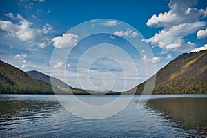 Calm landscape of mountain lake and beautiful deep blue sky with clouds in summer / autumn season.