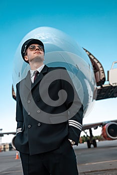 Calm male pilot in uniform waiting for flight in airport