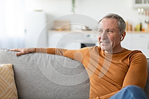 Calm mature man having rest at home listening to music