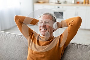 Calm mature man having rest at home listening to music
