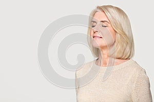 Calm mature woman inhaling taking deep breath of fresh air