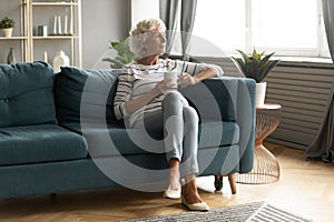 Calm mature woman relax on couch drinking tea