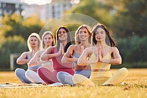 Calm meditation in lotus pose. Group of women have fitness outdoors on the field together