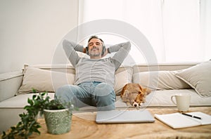 Calm Middle age Caucasian man sitting on sofa listening to music enjoying meditation for sleep and peaceful mind in wireless