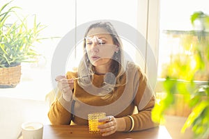 Calm middle-aged woman with lit match lighting candle while sitting at table in cozy room at home