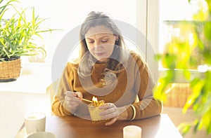 Calm middle-aged woman with lit match lighting candle while sitting at table in cozy room at home