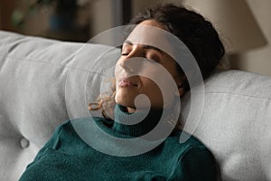 Calm millennial latina woman taking break for relax on couch