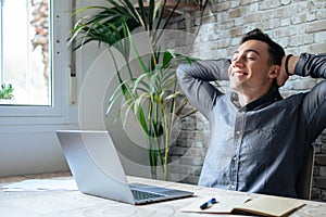 Calm millennial man in glasses sit relax at home office workplace take nap or daydream. Happy relaxed Caucasian young male rest in