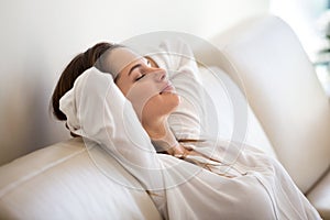 Calm millennial woman relaxing on comfortable sofa breathing fre photo