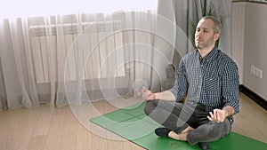 Calm mindful young man meditate in his living room