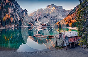 Calm morning view of Braies Pragser Wildsee lake with boats and fishing dock.