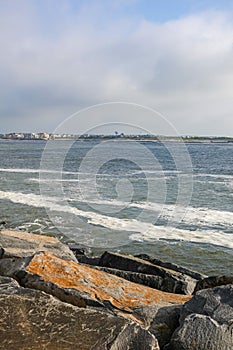 Calm ocean inlet with boulder jetty as dark storm clouds approach