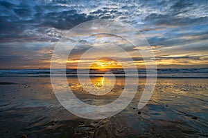 Calm ocean during the low tide in Oxnard California with the golden sunset shining in the background