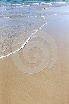 Calm ocean waves washing sand at the beach