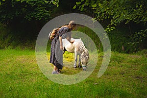 Calm peaceful fairy tale photography tender woman with pony in green grass meadow on forest edge in spring clear weather day
