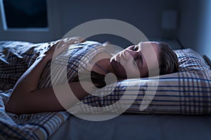 Calm and peaceful woman sleeping in bed in dark bedroom. Lady asleep at home in the middle of the night.