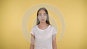 Calm peaceful woman on yellow background in studio isolated. Middleweight woman in basic white t-shirt