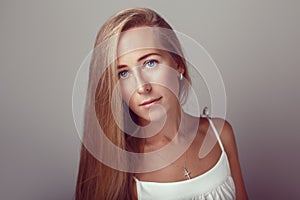 Calm pensive Caucasian blonde young beautiful girl woman model with long hair and blue eyes in white dress