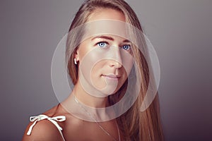 Calm pensive Caucasian blonde young beautiful girl woman model with long hair and blue eyes in white dress