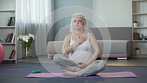Calm pregnant woman listening to sensations and touches of baby in her belly