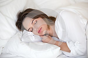 Calm pretty woman sleeping peacefully on white sheets in bed