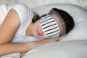Calm relaxed millennial woman sleeping in bed wearing stylish eyemask photo