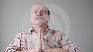 Calm relaxes senior hispanic man standing with palm hands, closed eyes and doing yoga meditating.