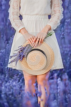 Calm scene with hands of young woman holding straw hat and lavender bouquet in hands