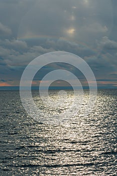 Calm sea and blue sky with white cirrus clouds. The sun shines through the clouds.