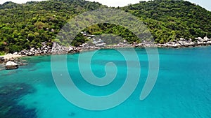 Calm sea near tropical volcanic island. Drone view of peaceful water of blue sea near stony shore and green jungle of