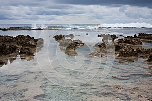 Calm sea with rocks in the foreground and waves in the background in Tonga