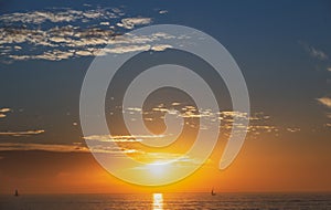 Calm sea with sunset sky and sun through the clouds over. Ocean and sky background, seascape.