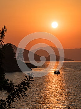 Calm sea and sunset. Sun is setting behind the hills on the horizont. Beautiful nature background