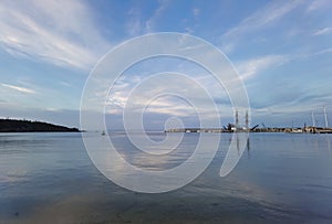Calm sea water and beautiful cloudy sky reflections on the harbor. Water landscape