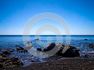 Calm Sea Water Wave Of Tropical Rocky Beach In The Clear Blue Sky On A Sunny Day