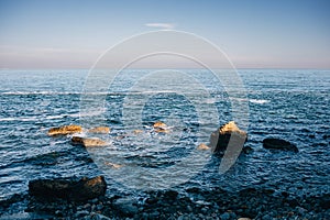 Calm seascape with rocky beach at sunrise