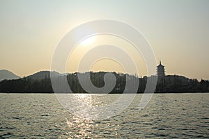 A calm seascape with trees, mountains and a Chinese Temple under the sun. Beautiful sunset.