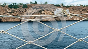 Calm Seascape View Through a Rope Net on a Cloudy Day at the Coastal Cliffside